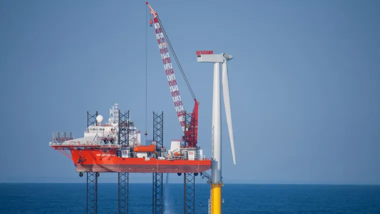 A large red and white oil rig in the ocean.