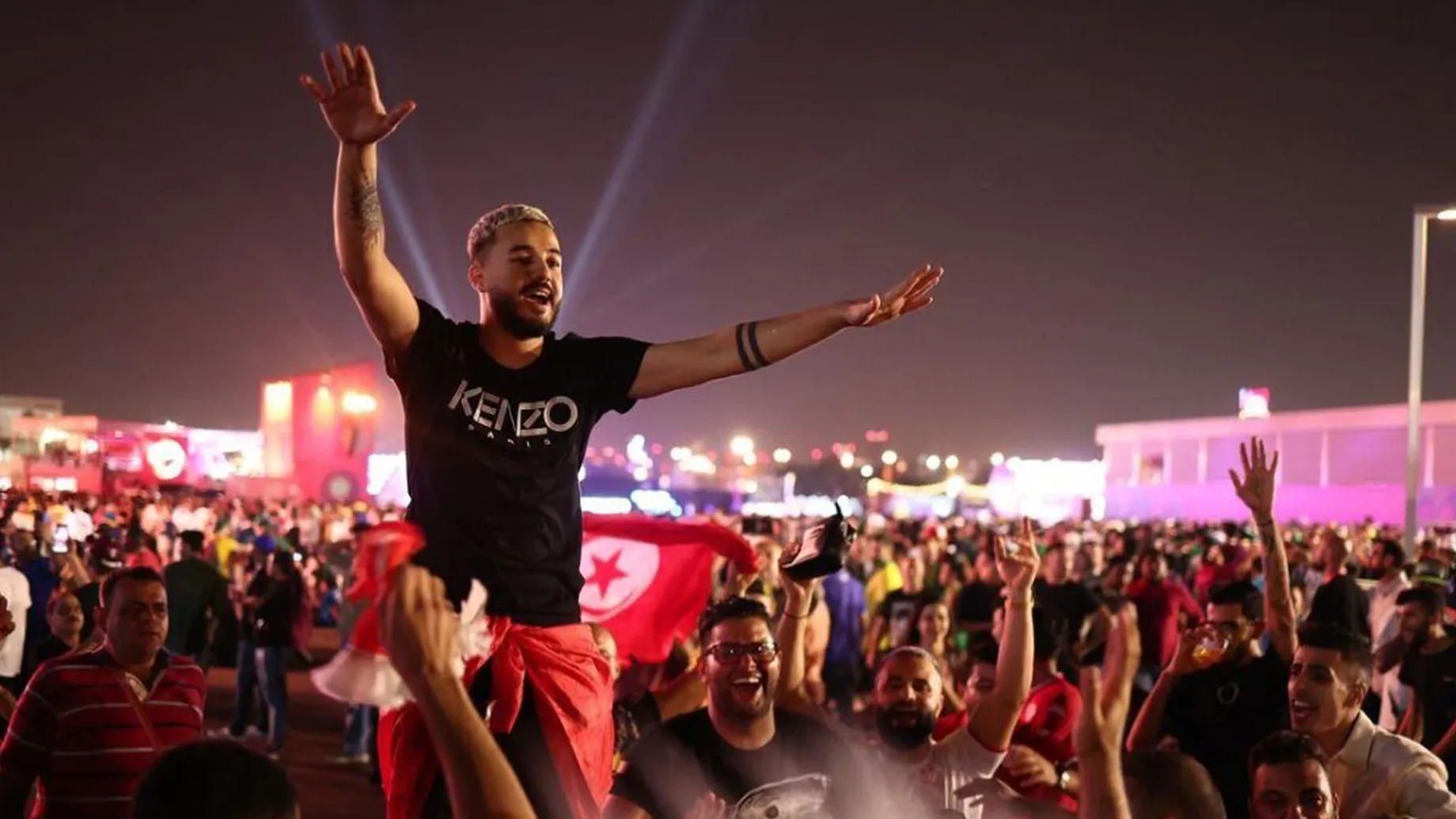 A person with the arms raised in front of a crowd.
